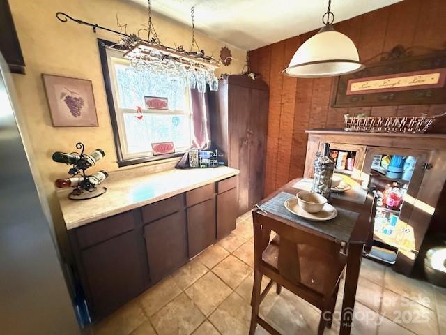 kitchen featuring light countertops, wooden walls, light tile patterned flooring, and pendant lighting