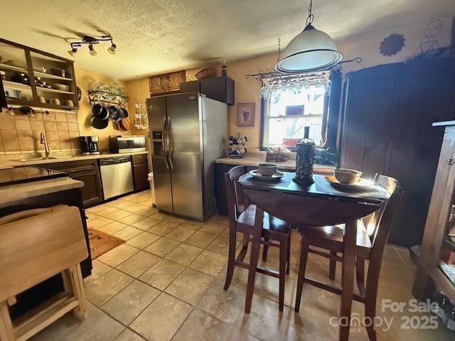 kitchen featuring a textured ceiling, light countertops, appliances with stainless steel finishes, and a sink