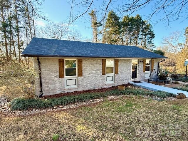 single story home with a front lawn, brick siding, and roof with shingles