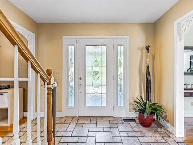 entryway featuring stairs, stone tile floors, and baseboards