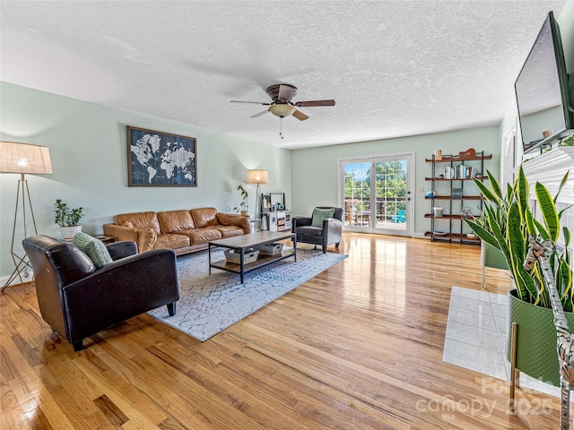 living area featuring light wood-style flooring, a textured ceiling, and a ceiling fan