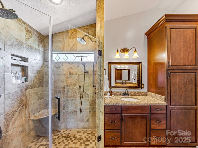 bathroom featuring lofted ceiling, a stall shower, and vanity