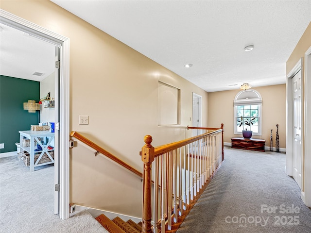 hallway featuring an upstairs landing, baseboards, and carpet floors