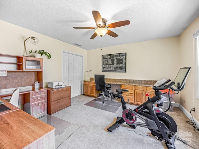 office area with baseboards, visible vents, ceiling fan, a textured ceiling, and light colored carpet