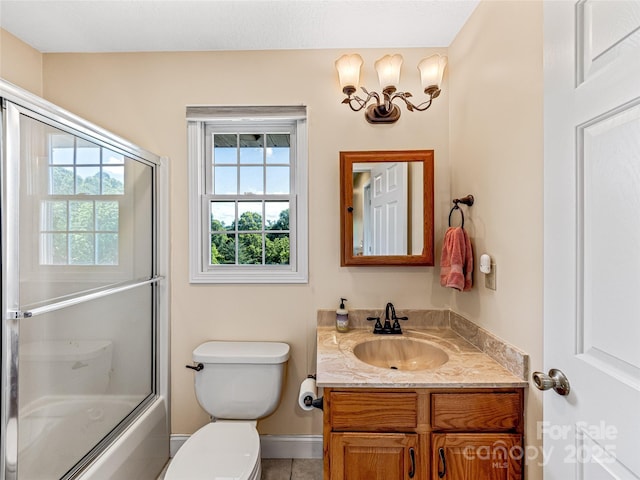 bathroom with toilet, vanity, and bath / shower combo with glass door