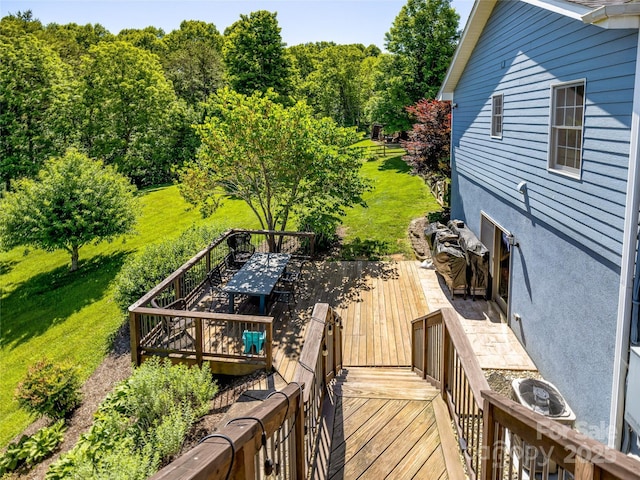 wooden terrace with outdoor dining area and a lawn