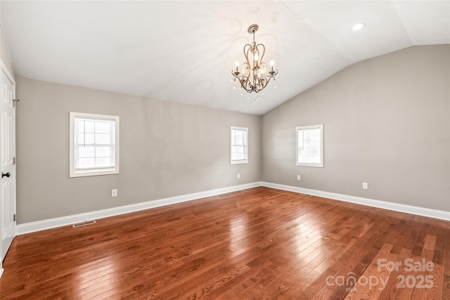 spare room featuring visible vents, a notable chandelier, hardwood / wood-style flooring, baseboards, and lofted ceiling