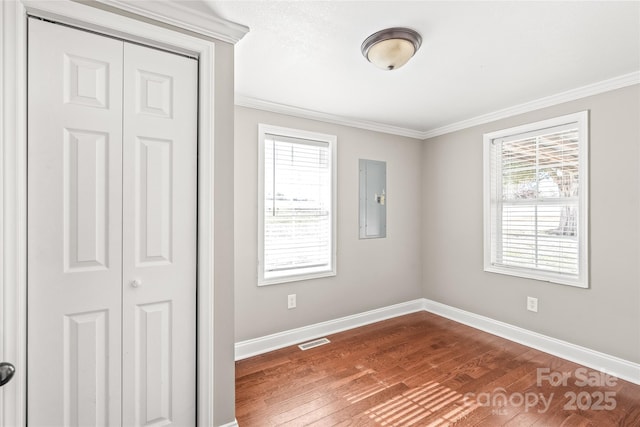 unfurnished bedroom featuring electric panel, visible vents, multiple windows, and baseboards