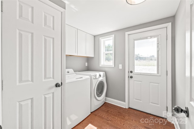 laundry room featuring washer and dryer, wood finished floors, cabinet space, and baseboards