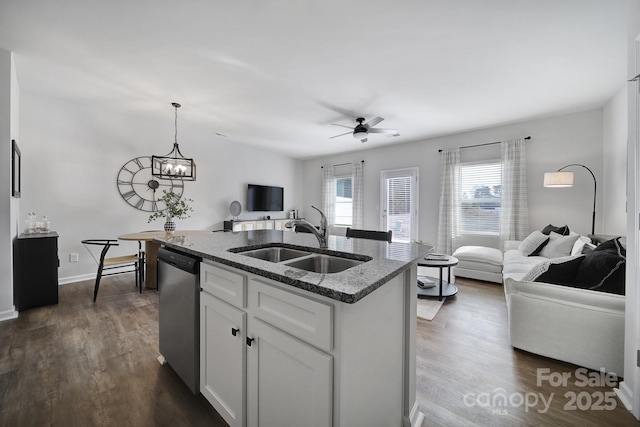 kitchen with dark stone countertops, dark wood finished floors, a sink, stainless steel dishwasher, and open floor plan