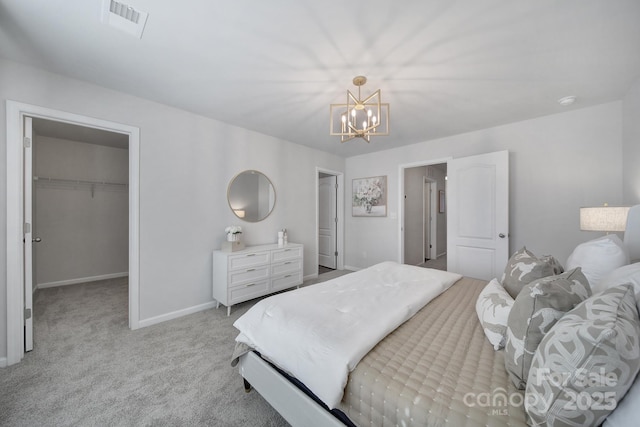 bedroom featuring a spacious closet, visible vents, baseboards, light carpet, and an inviting chandelier