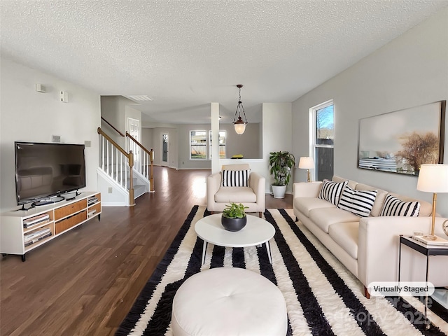 living area featuring stairs, wood finished floors, a wealth of natural light, and a textured ceiling