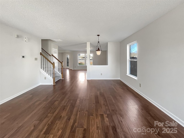 unfurnished living room featuring a textured ceiling, stairs, baseboards, and dark wood-style flooring