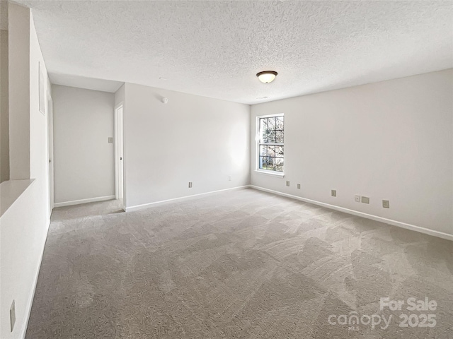 spare room featuring carpet, baseboards, and a textured ceiling