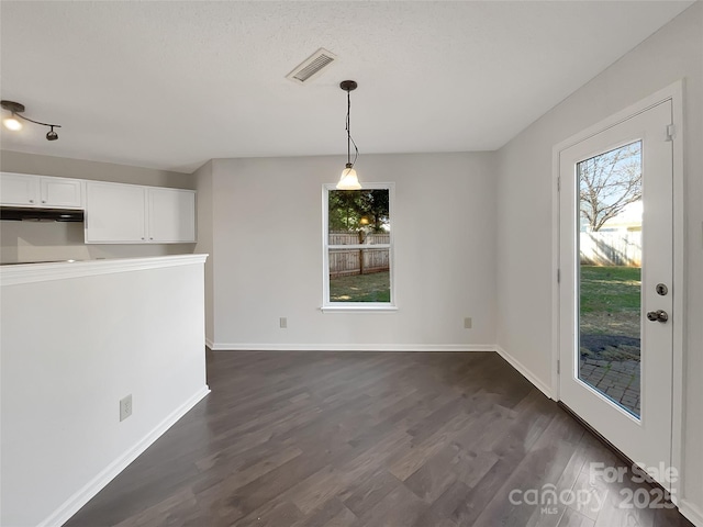 unfurnished dining area with visible vents, baseboards, and dark wood-style flooring