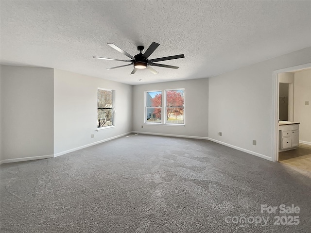 unfurnished bedroom with a textured ceiling, connected bathroom, carpet flooring, baseboards, and ceiling fan