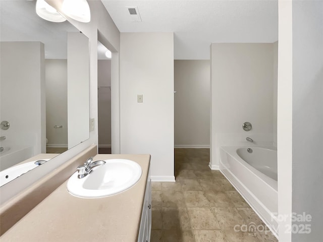 full bath featuring baseboards, visible vents, vanity, and a garden tub