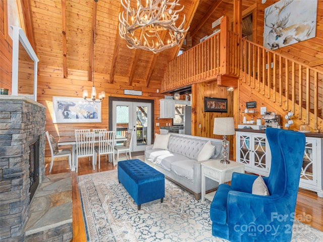 living room with beamed ceiling, a chandelier, wood ceiling, wood finished floors, and wood walls