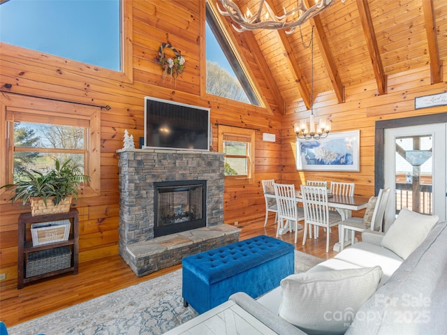 living room featuring wood finished floors, a notable chandelier, beam ceiling, and a healthy amount of sunlight