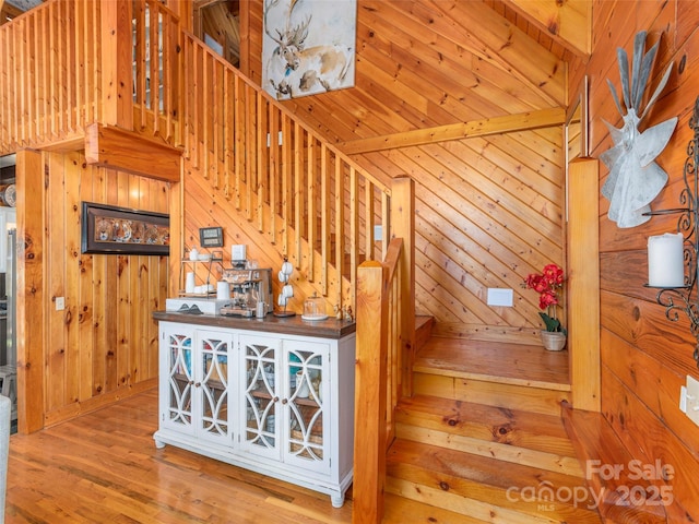 staircase featuring wood finished floors and wooden walls