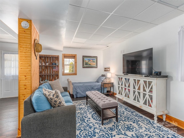 living room featuring a paneled ceiling, baseboards, visible vents, and wood finished floors