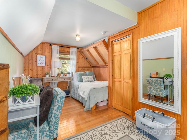 bedroom featuring wooden walls, vaulted ceiling, and wood finished floors