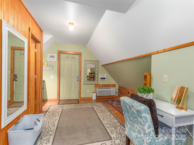 foyer featuring a wall mounted AC, vaulted ceiling, and wood finished floors