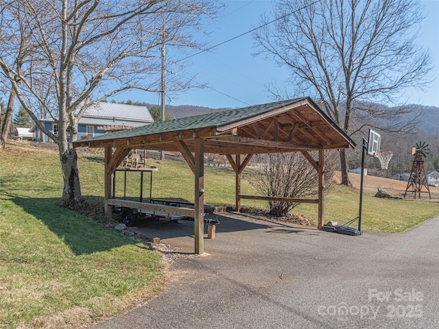 view of home's community with a carport, a lawn, and aphalt driveway