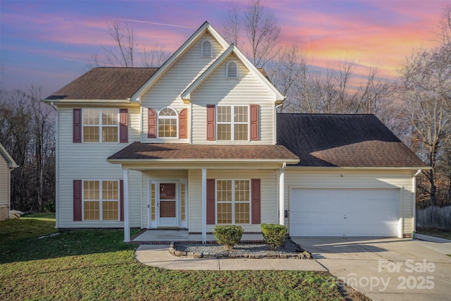 traditional home featuring driveway, a front lawn, covered porch, roof with shingles, and an attached garage