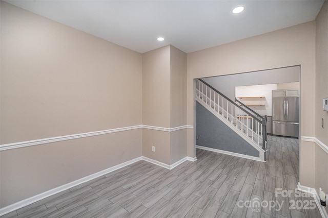 empty room with stairway, recessed lighting, baseboards, and wood finished floors