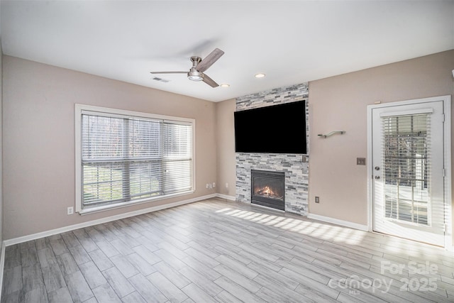 unfurnished living room with visible vents, wood finished floors, a fireplace, baseboards, and ceiling fan