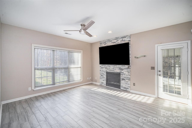 unfurnished living room with visible vents, baseboards, ceiling fan, a fireplace, and wood finished floors