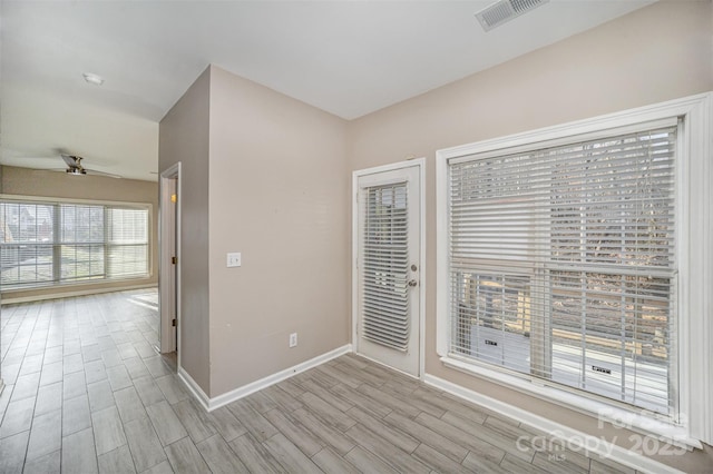 spare room with a ceiling fan, baseboards, visible vents, and wood finish floors