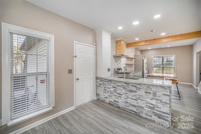 kitchen with a sink, visible vents, a peninsula, and wood tiled floor