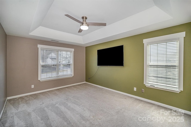 spare room with a raised ceiling, carpet flooring, and baseboards