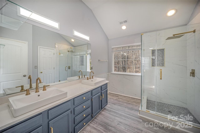 bathroom featuring vaulted ceiling, visible vents, wood finished floors, and a sink