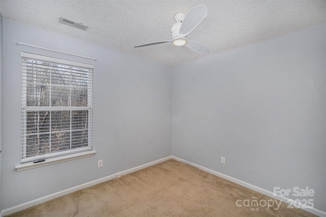 unfurnished room with carpet, baseboards, visible vents, ceiling fan, and a textured ceiling