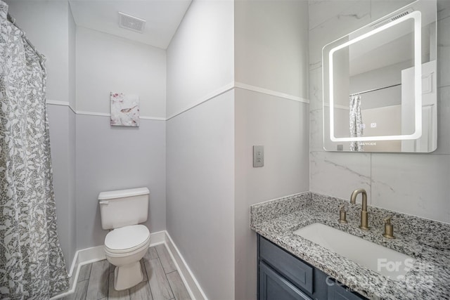 bathroom featuring visible vents, toilet, vanity, baseboards, and wood tiled floor