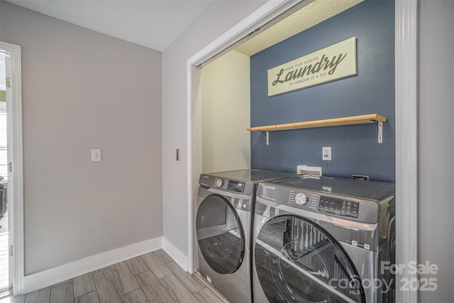 clothes washing area with baseboards, laundry area, wood tiled floor, and washer and clothes dryer