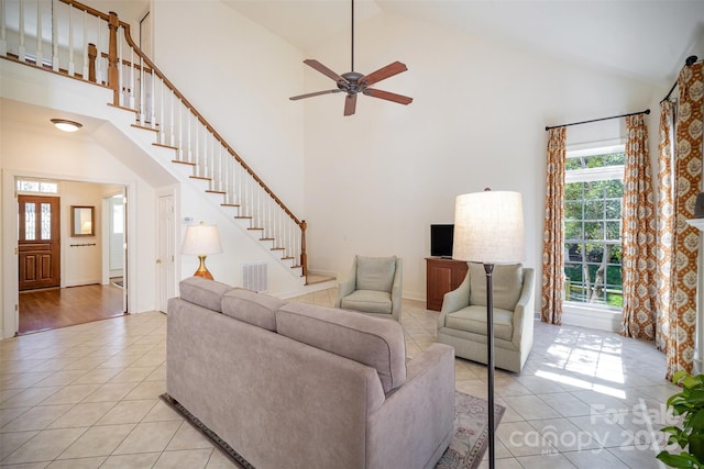 living room with light tile patterned flooring, high vaulted ceiling, a ceiling fan, visible vents, and stairway