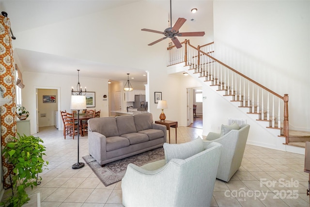 living area with high vaulted ceiling, ceiling fan with notable chandelier, stairs, light tile patterned floors, and visible vents