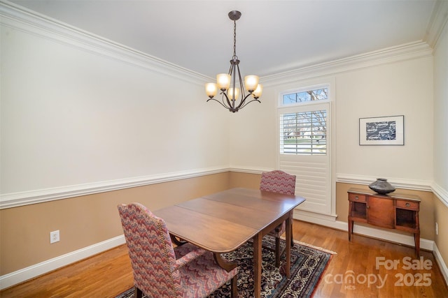 dining area featuring crown molding, baseboards, an inviting chandelier, and light wood-type flooring
