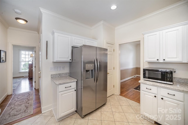 kitchen featuring white cabinets, crown molding, stainless steel fridge, and baseboards