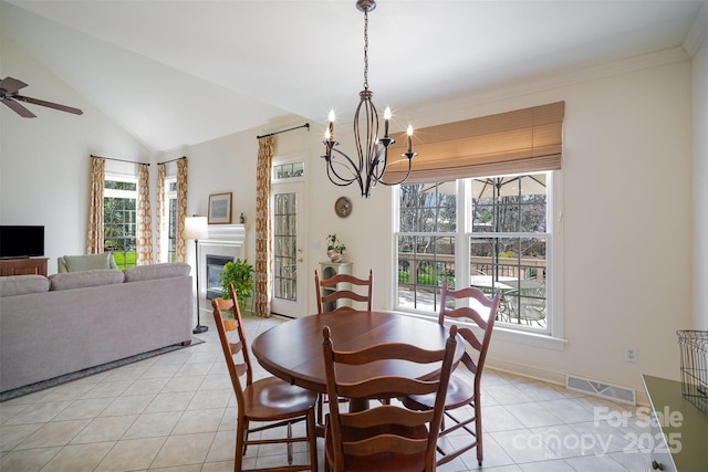 dining space with visible vents, vaulted ceiling, light tile patterned floors, ceiling fan with notable chandelier, and a glass covered fireplace