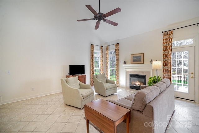 living room with light tile patterned flooring, a fireplace, baseboards, ceiling fan, and high vaulted ceiling