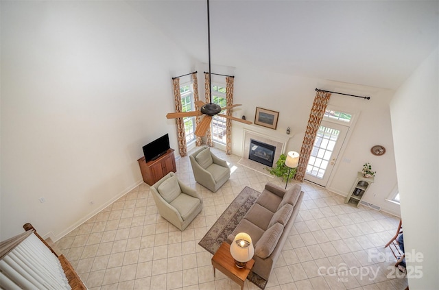 living room featuring light tile patterned flooring, high vaulted ceiling, baseboards, and a tile fireplace