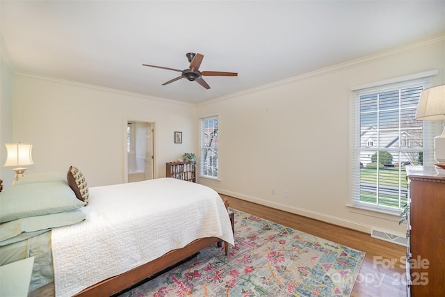 bedroom with visible vents, baseboards, crown molding, and wood finished floors