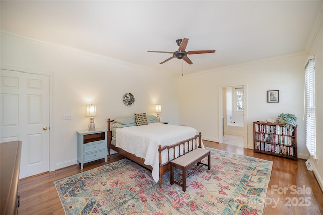 bedroom featuring baseboards, ornamental molding, wood finished floors, and ensuite bathroom