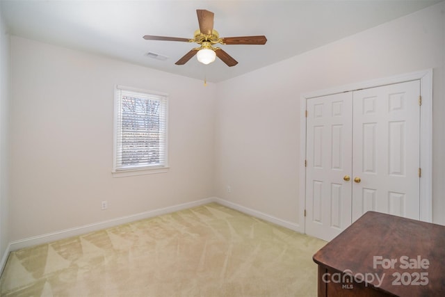 unfurnished bedroom featuring visible vents, a closet, light carpet, baseboards, and a ceiling fan
