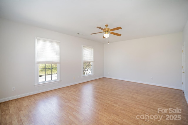 spare room featuring light wood-type flooring, a ceiling fan, baseboards, and visible vents
